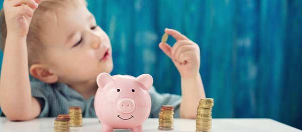 Little boy putting coins in piggy bank