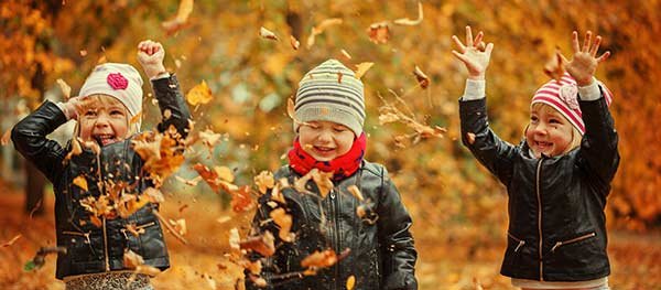 Little kids playing with fall leaves
