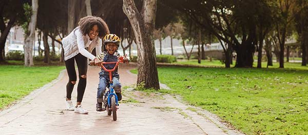 Mom helping daughter learn to ride a bike