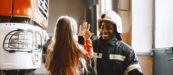 Firefighter in front of engine with small girl