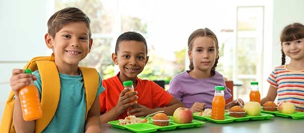 Four small children with lunch trays at school