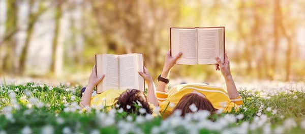 Mother and child lying in a field reading books