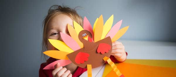 Small child holding construction paper turkey