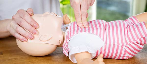 Person practicing CPR on dummy infant