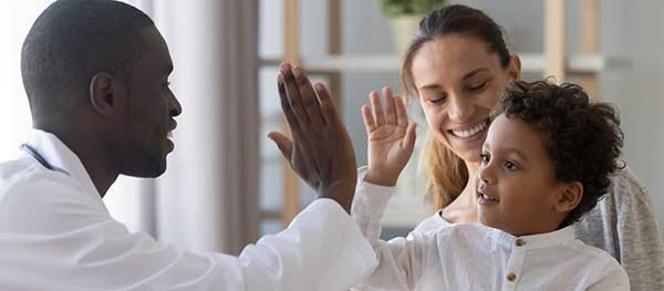 Mom and son high-fiving a doctor