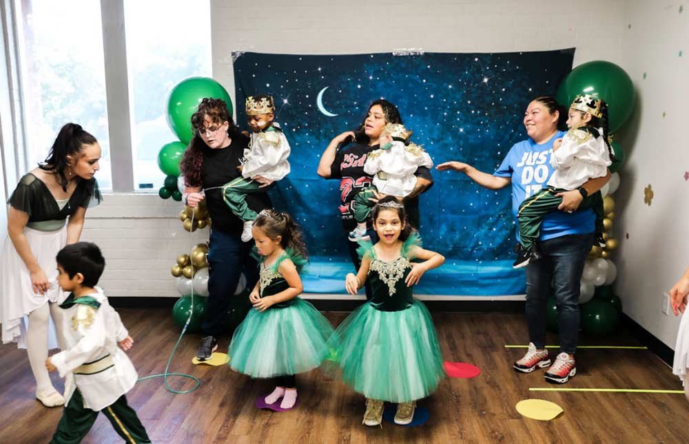 Group of small children at recital in costumes with teachers and parents
