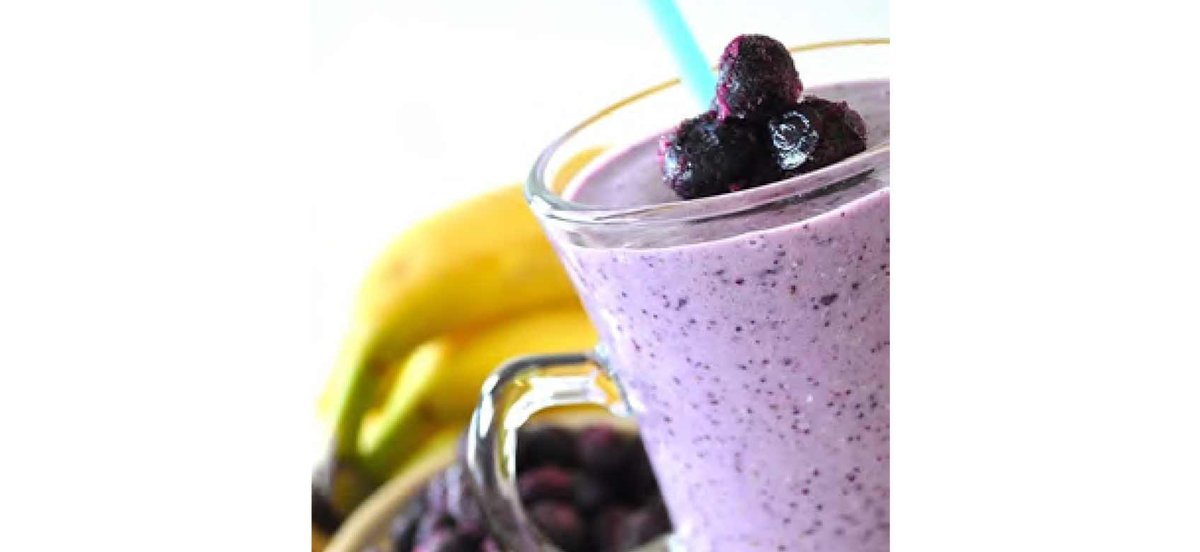 Purple smoothie with blueberries in clear glass