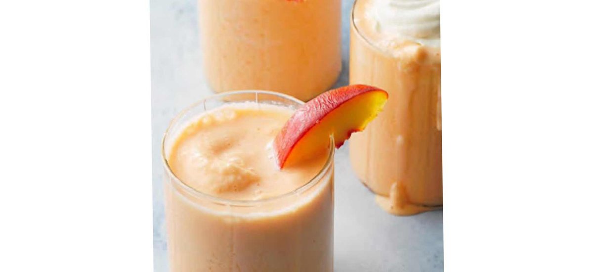 Peach shake with slice of peach on the rim